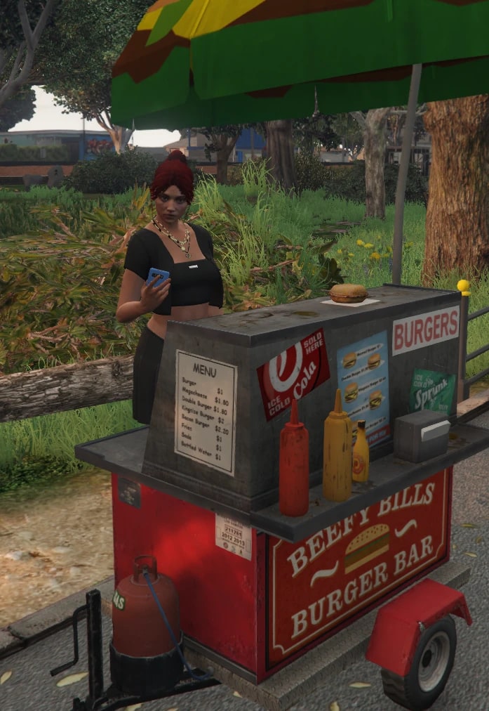 A woman checks her phone behind a red roadside burger cart under a striped umbrella in Paleto Bay